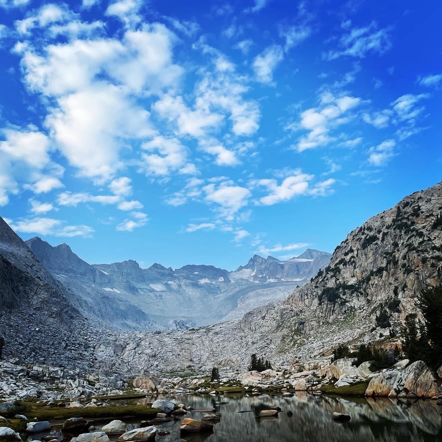 a mountain range against a blue sky with white clouds